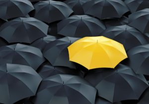 yellow umbrella on the background of black umbrellas